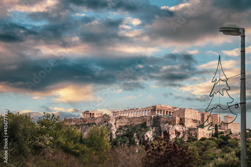 Looking up at the Parthenon on the Accropolis in Athens Greece under sunset sky with Christmas tree street decoration in foreground. photo