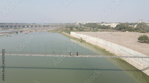 Drone flies high in the sky above floating clouds. Below, overlooks an impressive view of the Hanging bridge near machhu dam, Aerial. 4K photo