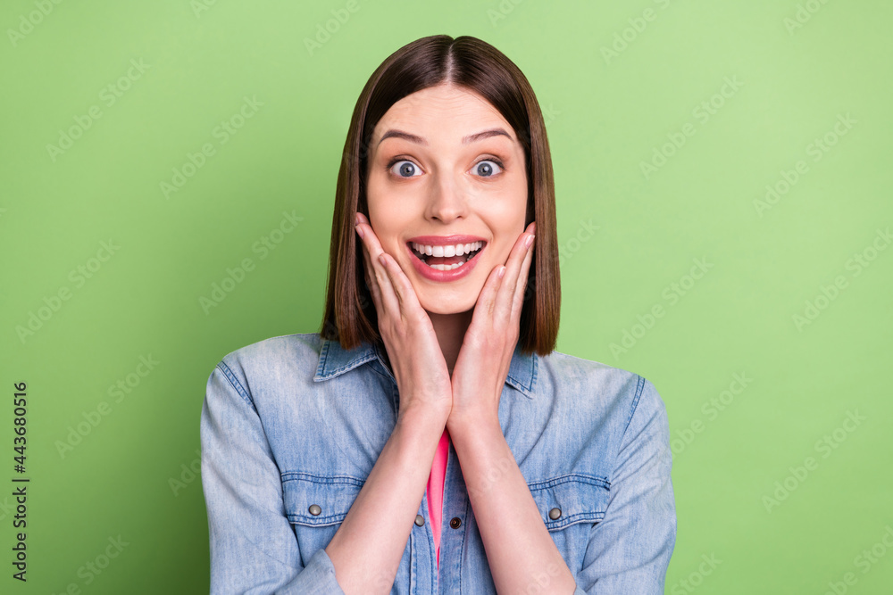 Photo of hooray brunette hair young lady hands face wear jeans jacket isolated on green color background Photo of hooray brunette hair young lady hands face wear jeans jacket isolated on green color background