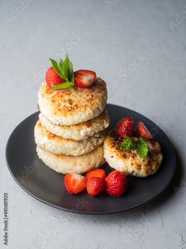 Cottage cheese pancakes with strawberries, mint and sour cream on a light background. syrniki. healthy dessert