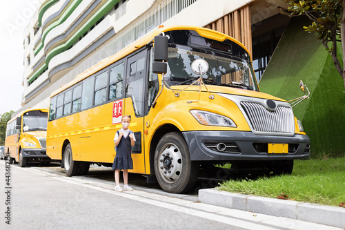 Back to school. Little girl from elementary school outdoor near yellow bus. Kid going learn new things 1th september