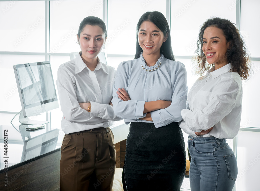 A group of multi-ethnic female startups is raising their fingers and looking at the camera after a planning meeting.