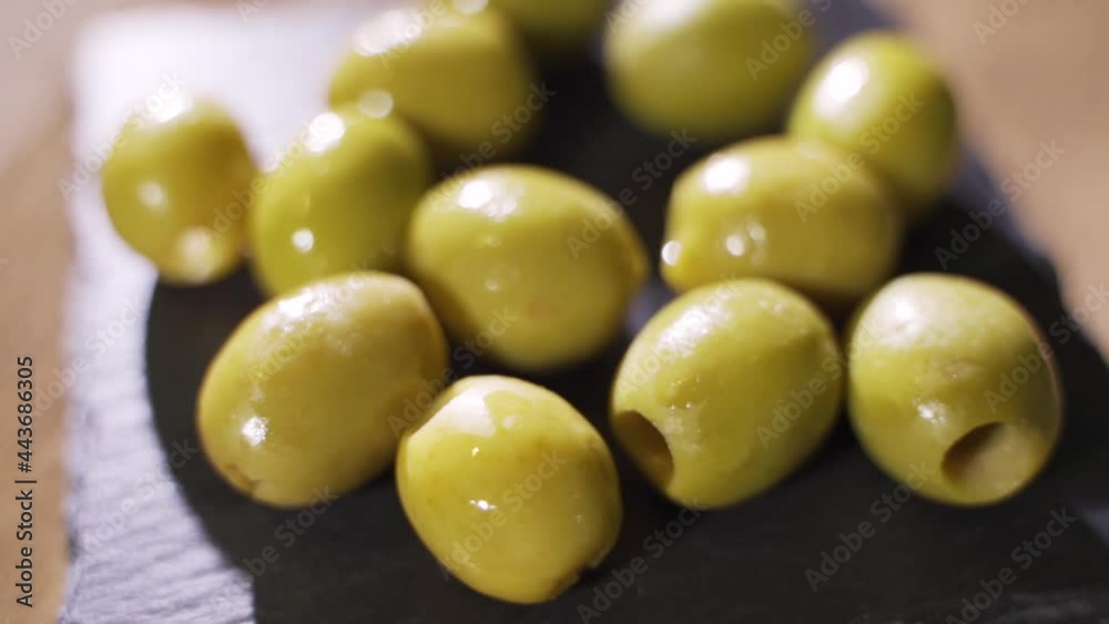 Olives on a black wooden board close-up. The camera rotates around. Delicious delicacy. Olives on a black wooden board close-up. The camera rotates around. Delicious delicacy.