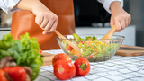 Close up of asian housewife wearing apron and using ladle to mixing vegetable salad in bowl while standing