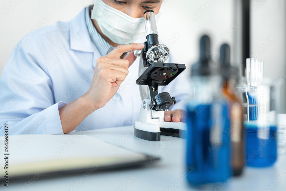 Scientist woman using microscope to analyzing and development coronavirus vaccine while working Scientist woman using microscope to analyzing and development coronavirus vaccine while working