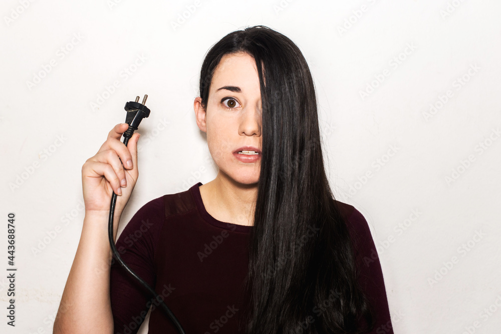 A brunette young girl holding an electrical plug. European type c plug
