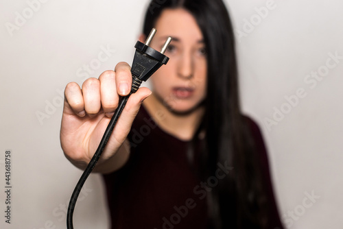 A brunette young girl holding an electrical plug. European type c plug on focus