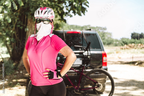 portrait of a woman with sportswear for cyclists, with helmet and glasses in the background her bicycle. adventure concept.