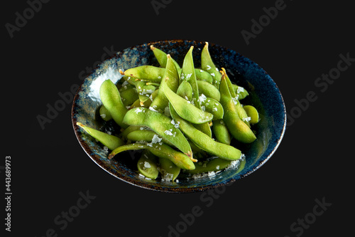 Edamame bean salad with sea salt served in a dark bowl. Isolated on a black background. Restaurant food. Japanese kitchen