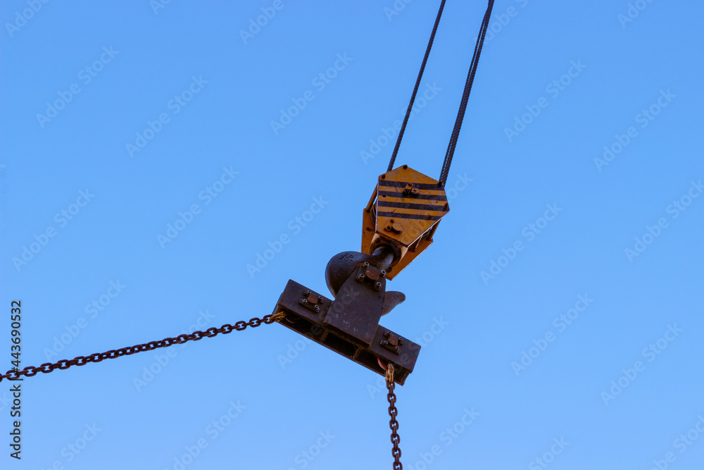 Slings and hook of a construction crane against a blue sky. Industrial background Slings and hook of a construction crane against a blue sky. Industrial background