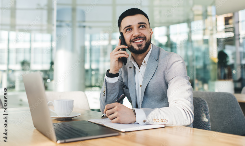 Smiling businessman talking on smartphone in modern office