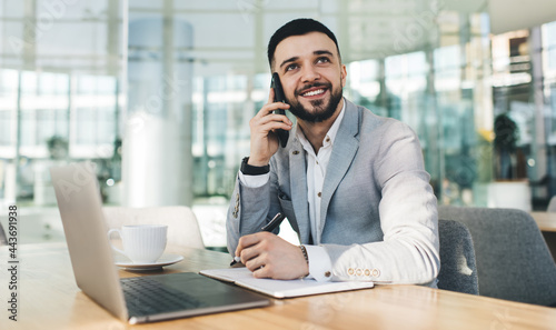 Smiling businessman talking on smartphone in modern office © BullRun