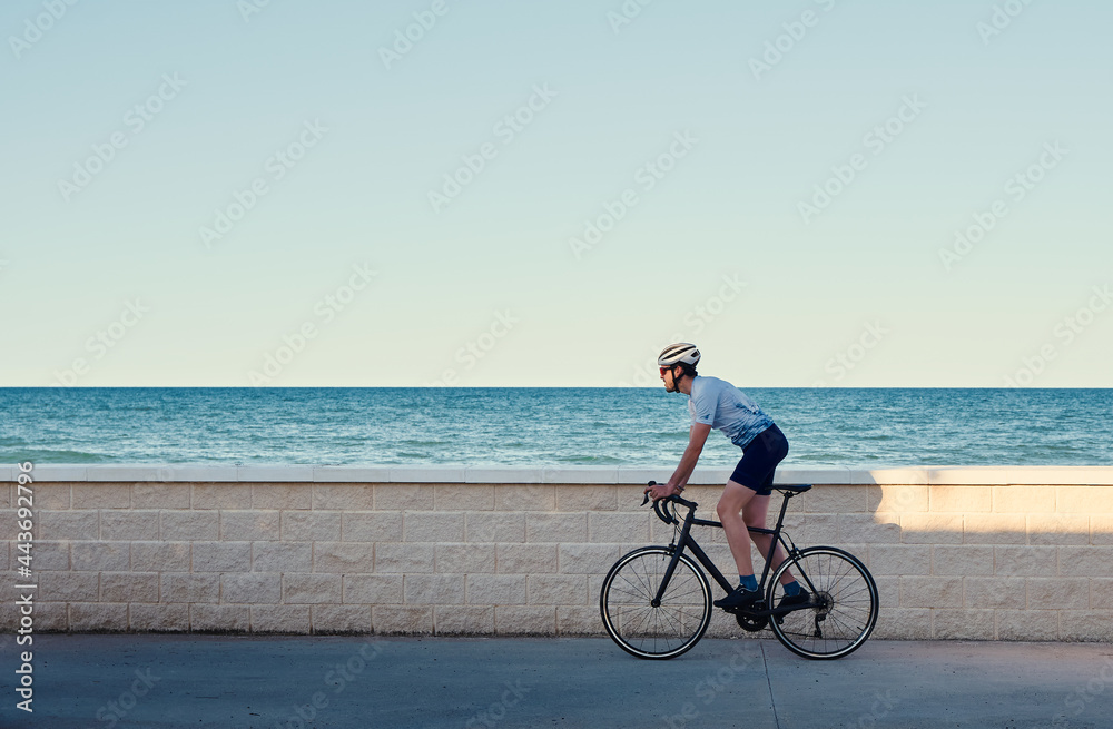 Young man riding a road bike overlooking the sea