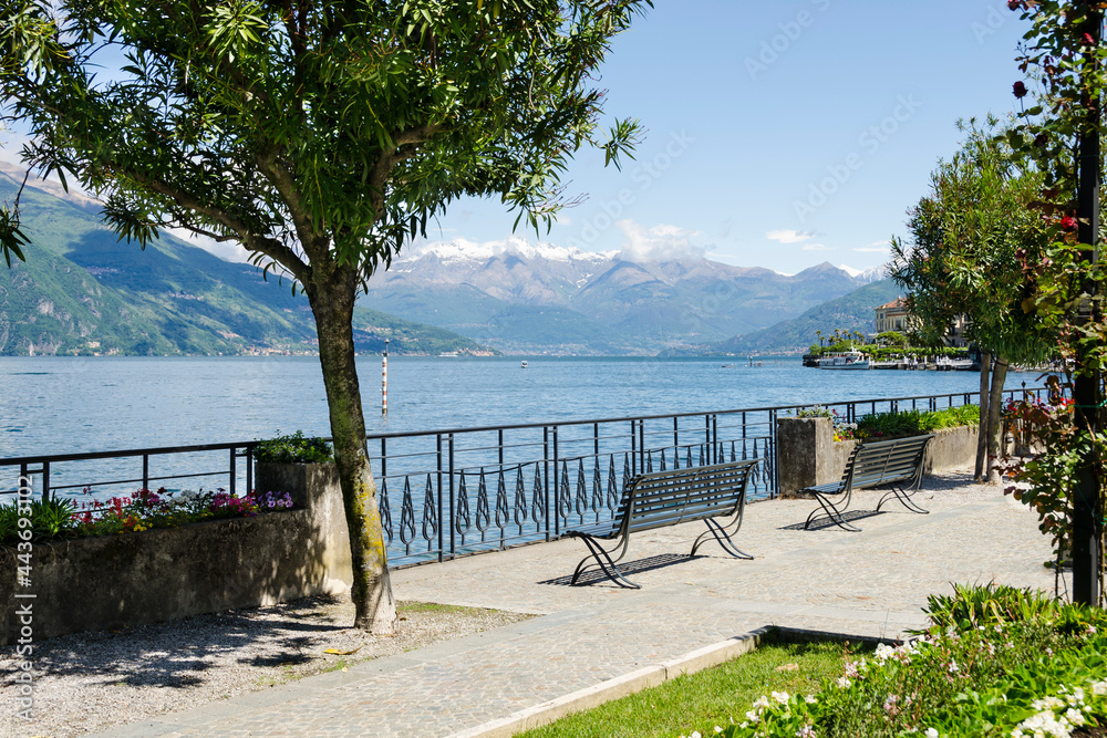 Two metal benches stand on the embankment of the lake overlooking the mountains