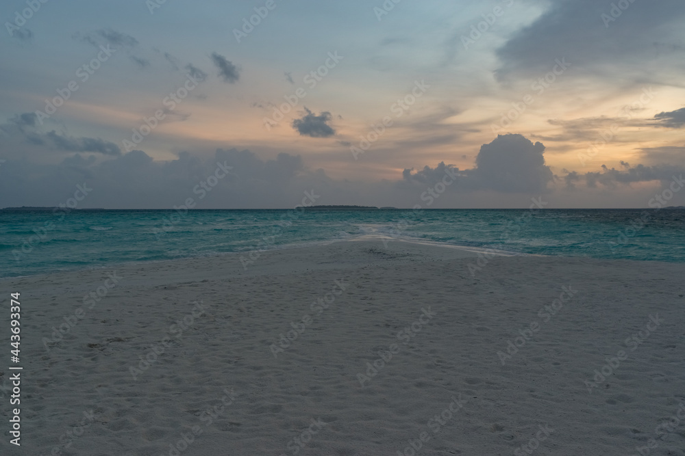 Obraz premium sandy coast of a coral island in the Indian Ocean at sunset in cloudy weather