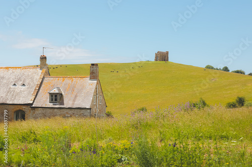 An old stone cottage and a distant St Catherine's Chapel  in the quaint rural countryside at the village of Abbotsbury on a sunny summer day in Dorset, England, UK. photo