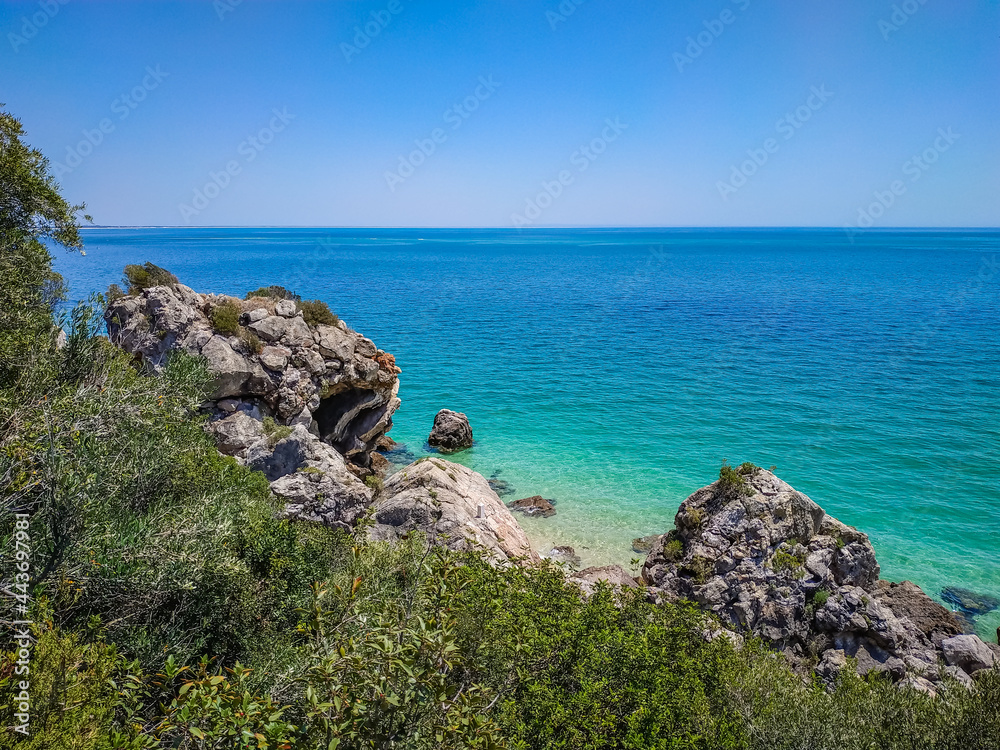 Vegetation and rocks with clear turquoise water from the Atlantic Ocean at Galapos beach, Arrábida - Setúbal PORTUGAL