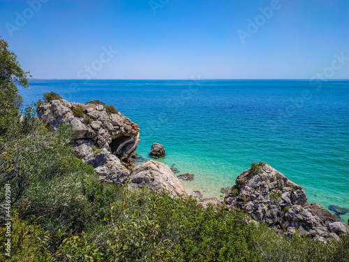 Vegetation and rocks with clear turquoise water from the Atlantic Ocean at Galapos beach, Arrábida - Setúbal PORTUGAL photo