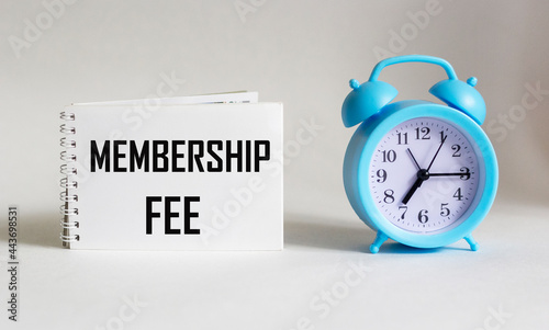 On notepad text about membership fee, business concept image on white background with alarm clock