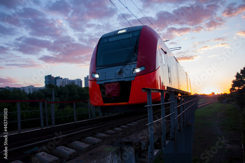 An electric train moving at high speed against the background of sunset.