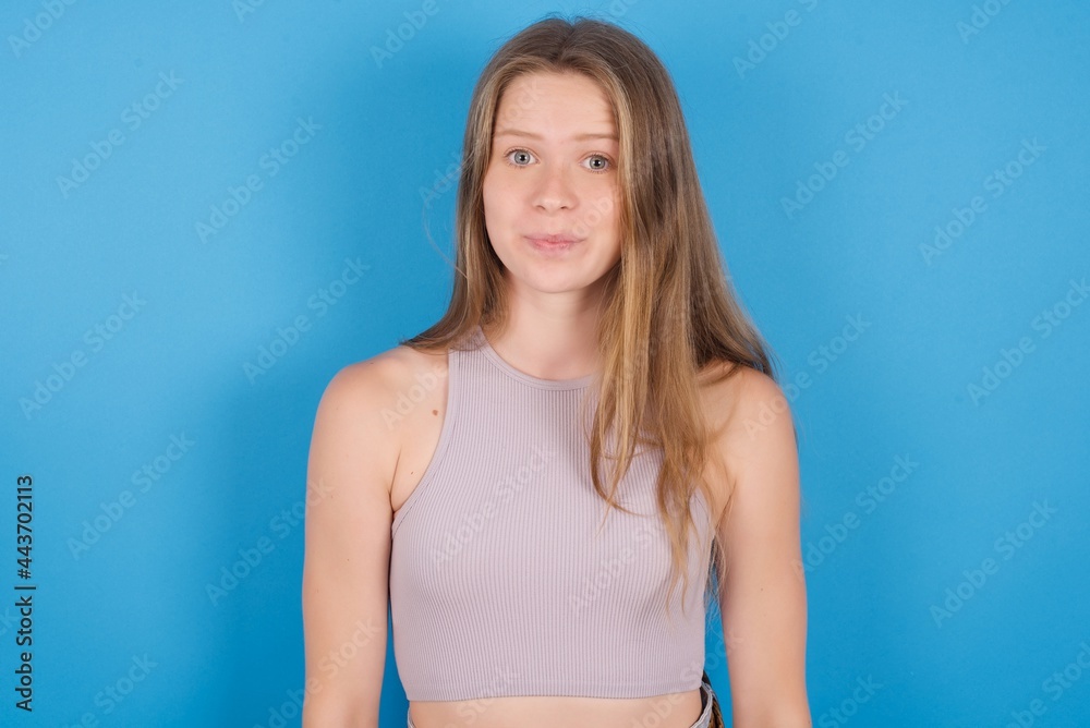 Stunned young beautiful blonde woman standing against blue background stares reacts on shocking news. Astonished girl holds breath Stunned young beautiful blonde woman standing against blue background stares reacts on shocking news. Astonished girl holds breath