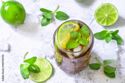 Refreshing summer cold drink. Cuba Libre alcoholic drink, Cola with ice cubes on a gray stone table top.