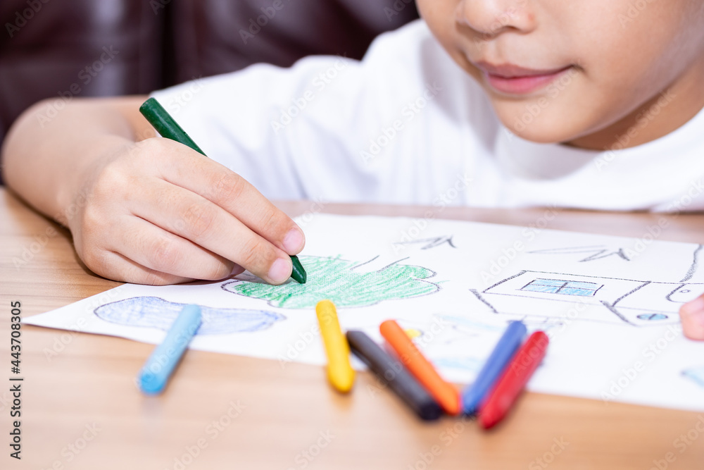 A little boy drawing a house with crayons is a beautiful imagination painting. A little child is engaged in creativity, the child does his homework. A little boy drawing a house with crayons is a beautiful imagination painting. A little child is engaged in creativity, the child does his homework.