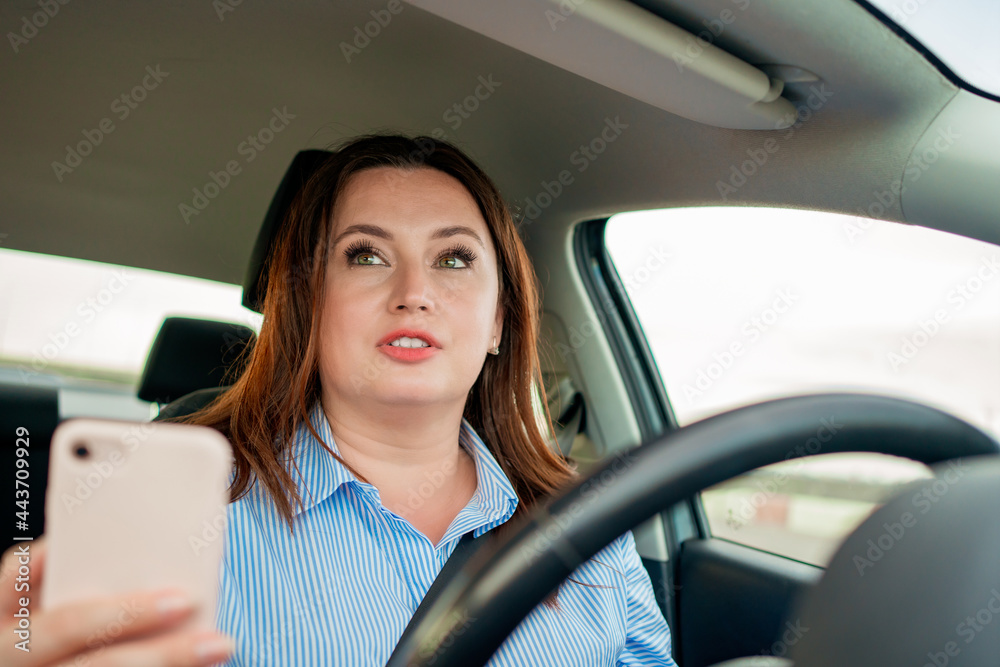 The woman driving the car drives the car and speaks on the phone.