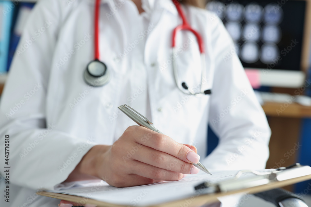 Doctor writing in medical documents on clipboard in clinic closeup Doctor writing in medical documents on clipboard in clinic closeup