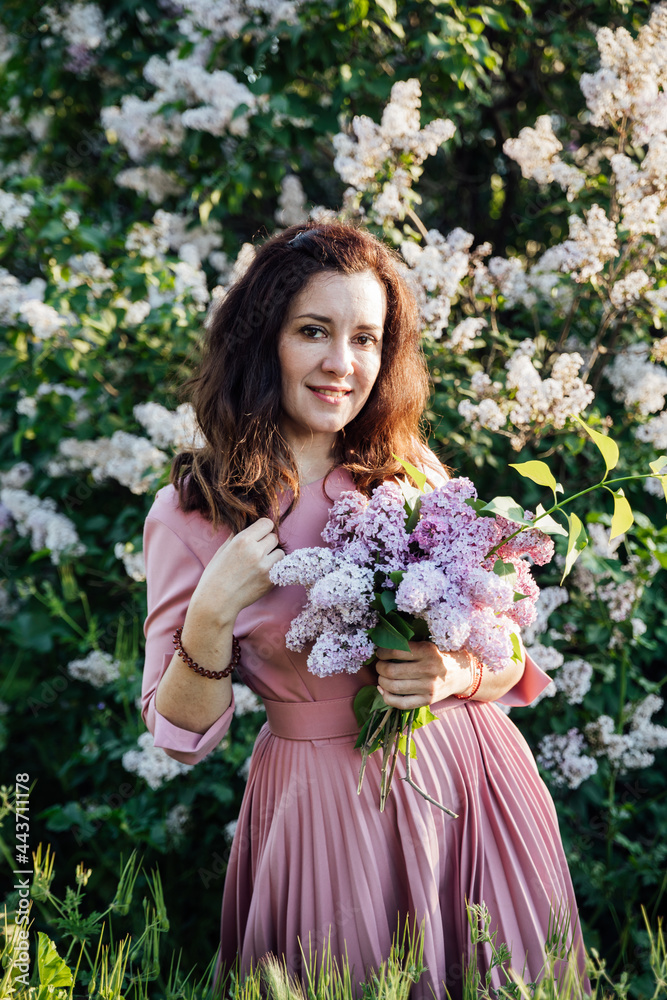 portrait of a beautiful brunette woman in a lilac dress with lilac flowers portrait of a beautiful brunette woman in a lilac dress with lilac flowers