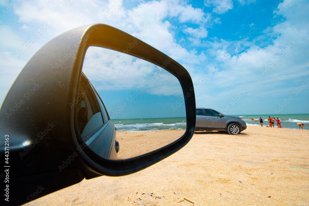 Sea view through the side mirror of the car. Car on the seashore.