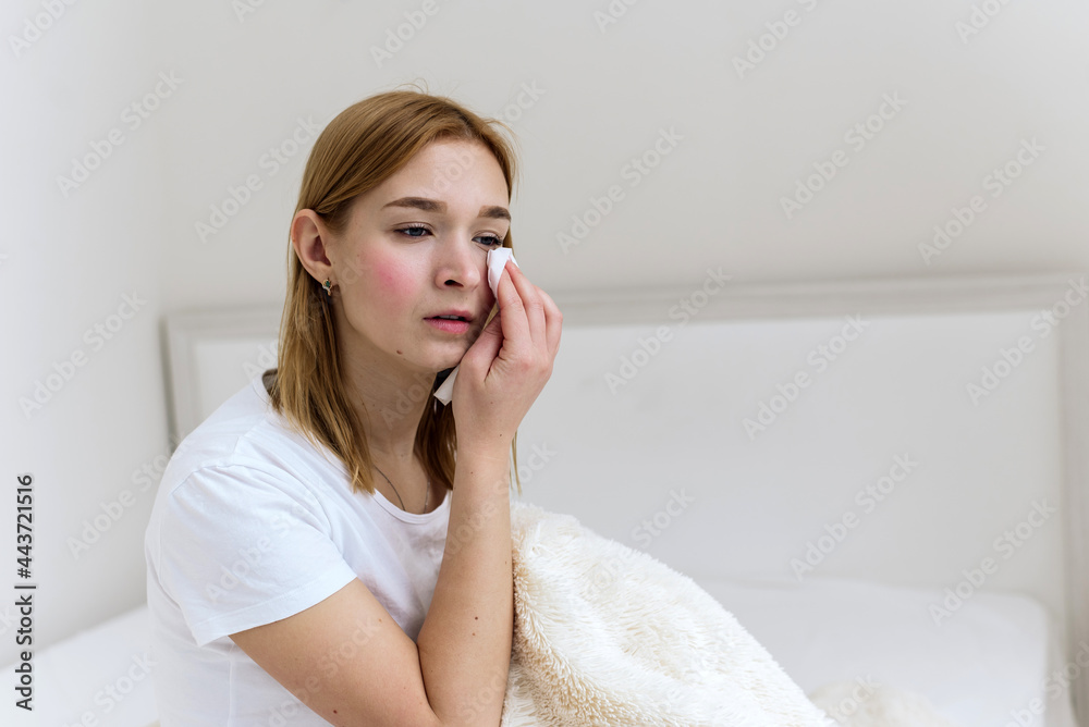 Broken heart, home concept. Sad woman wipes away tears from her face and crying. Lonely girl sitting on a bed of apartments Broken heart, home concept. Sad woman wipes away tears from her face and crying. Lonely girl sitting on a bed of apartments