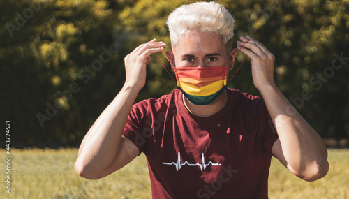 Obraz na plátně young gay man removing a mask with the drawing of the rainbow
