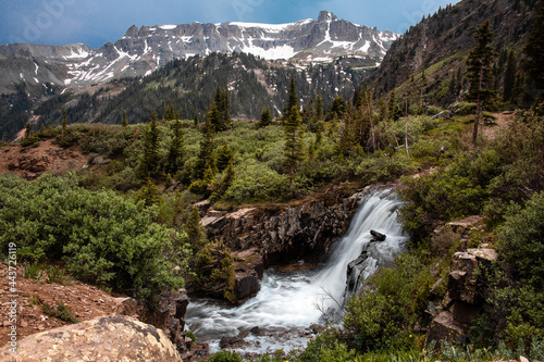 View of a waterfall surrounded by greenery  mountains  and trees in Yankee Boy Basin near Ouray  Colorado. 