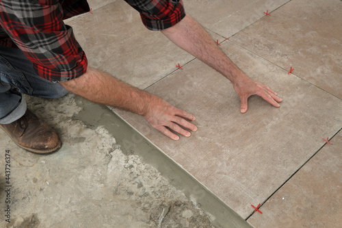 Worker placing ceramic tile to floor in a kitchen or bathroom