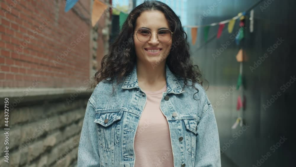 Portrait of attractive Asian woman wearing trendy glasses standing outdoors in city smiling looking at camera. Modern people and urban youth concept. Portrait of attractive Asian woman wearing trendy glasses standing outdoors in city smiling looking at camera. Modern people and urban youth concept.
