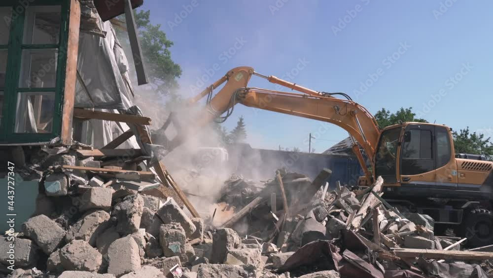 Excavator bucket loads trash and debris from destroyed building into truck. Demolition of house.