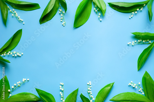 little bouquets of lilly of the valley as a floral frame with copy space. Flat lay with blue background. 