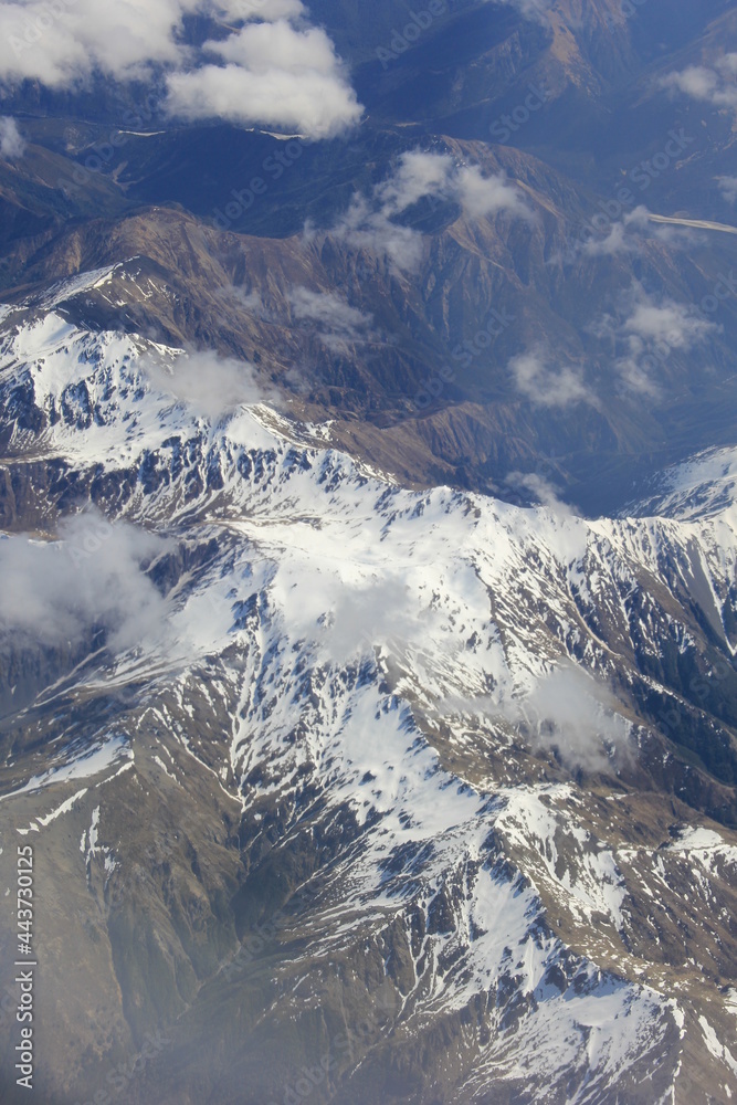 航空機の高度から見下ろした、冠雪した山々と雲