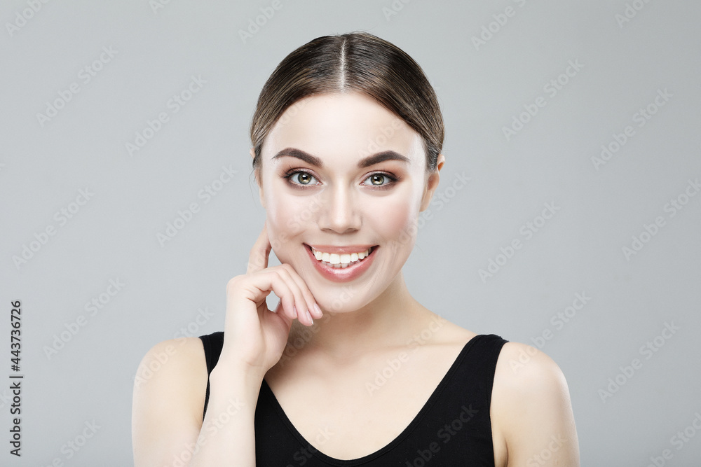 Close-up portrait of a smiling young woman, sporty style. Over grey background. Close-up portrait of a smiling young woman, sporty style. Over grey background.