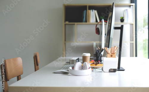 Creative designer workplace near window with computer, headphone and office supplies. © wattana