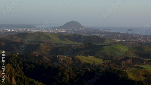 Panning wide shot of Mount Maunganui and main beach at sunrise shot from top of Papamoa Hills. Mount Maunganui, Tauranga, Bay of Plenty, New Zealand photo