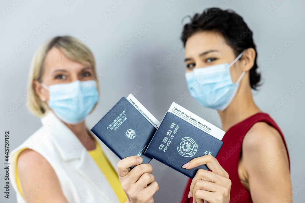 Female friends of different ages are ready for the summer vacation safely. Portrait in masked studio and raise an arm to record the vaccination record against COVID-19 Coronavirus vaccination concept. Female friends of different ages are ready for the summer vacation safely. Portrait in masked studio and raise an arm to record the vaccination record against COVID-19 Coronavirus vaccination concept.