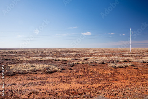 Bright colours & textures of the rocky desert with power lines on the horizon. South Australia.