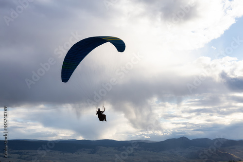Adventurous People Flying on a Paraglider around the mountains. Savona, British Columbia, Canada.