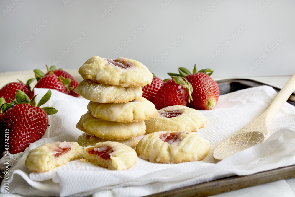 Homemade cookies filled with strawberry jam and strawberries on plate next to cookies. Homemade cookies filled with strawberry jam and strawberries on plate next to cookies.