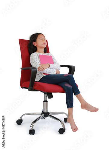Asian little girl child sleeping with hugging a book sitting on red fabric chair isolated over white background. Image in studio with Clipping path
