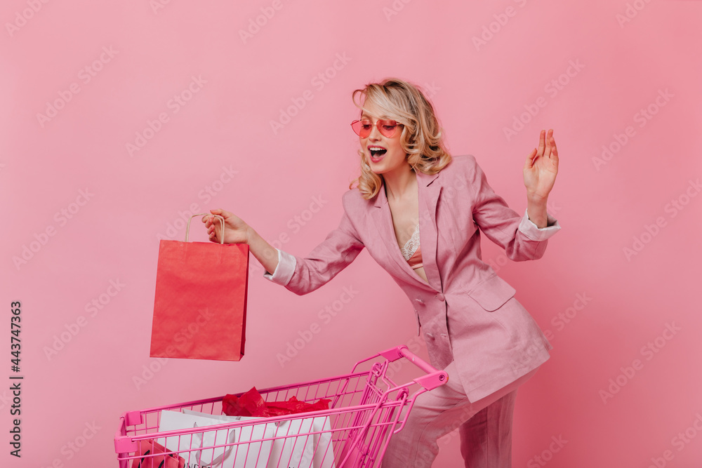 Cute woman in pink suit puts package in trolley