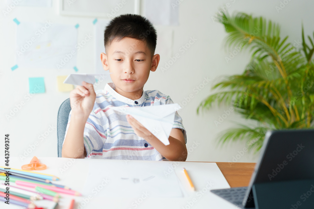 Asian boy playing paper airplane while sitting at home morning Asian boy playing paper airplane while sitting at home morning