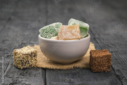 A few slices of Turkish delight in a white cup on a wooden table.